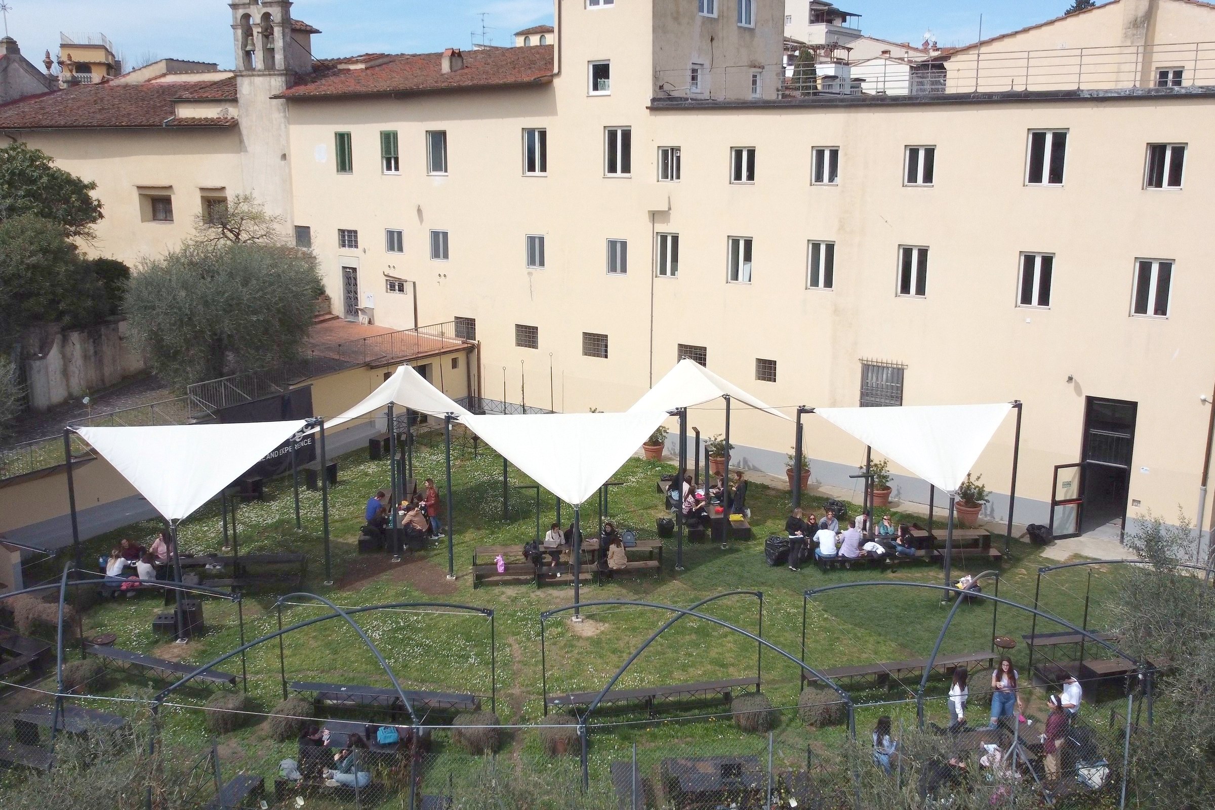 An outdoor lesson under the white canopies in the garden of the Florence campus