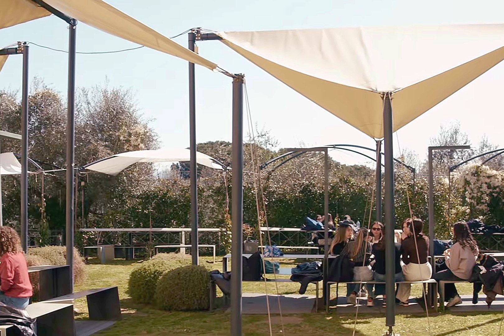 Students at the tables under the canopies in the Florence campus garden