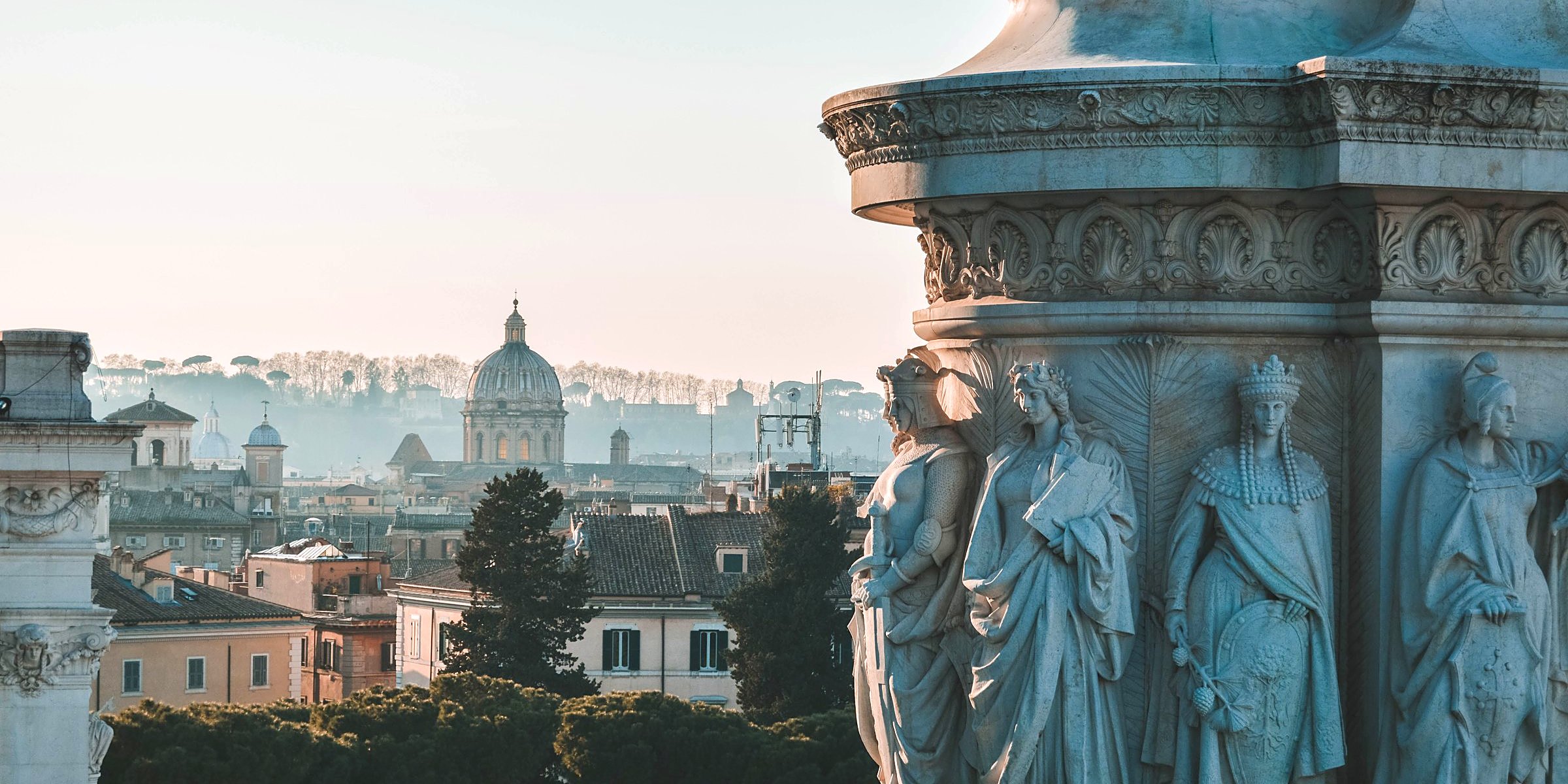 Rome's rooftops and a church dome beside a carved marble monument