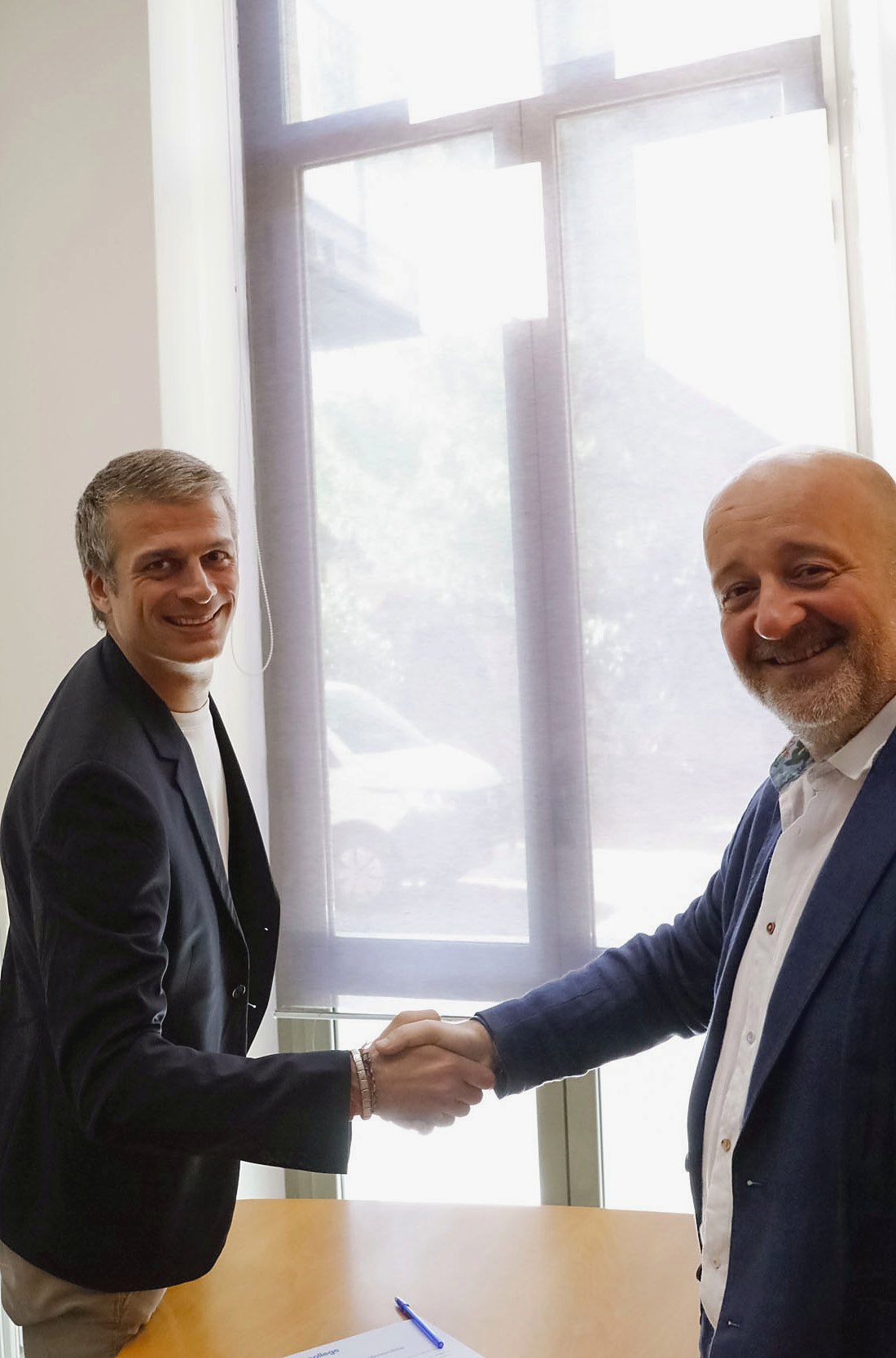A handshake sealing a university partnership at the Unicollege offices