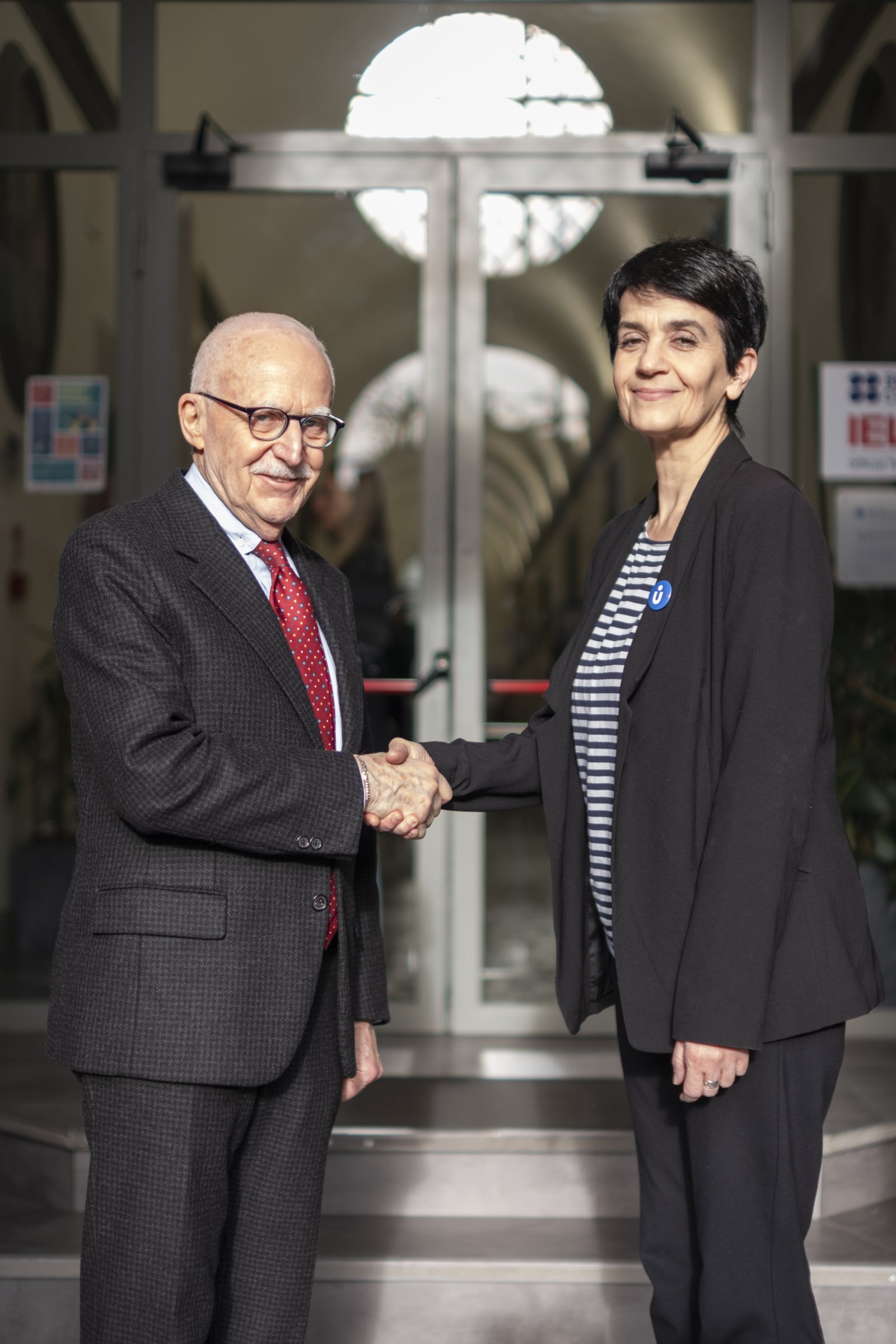 Two institutional representatives shaking hands at a Unicollege campus entrance