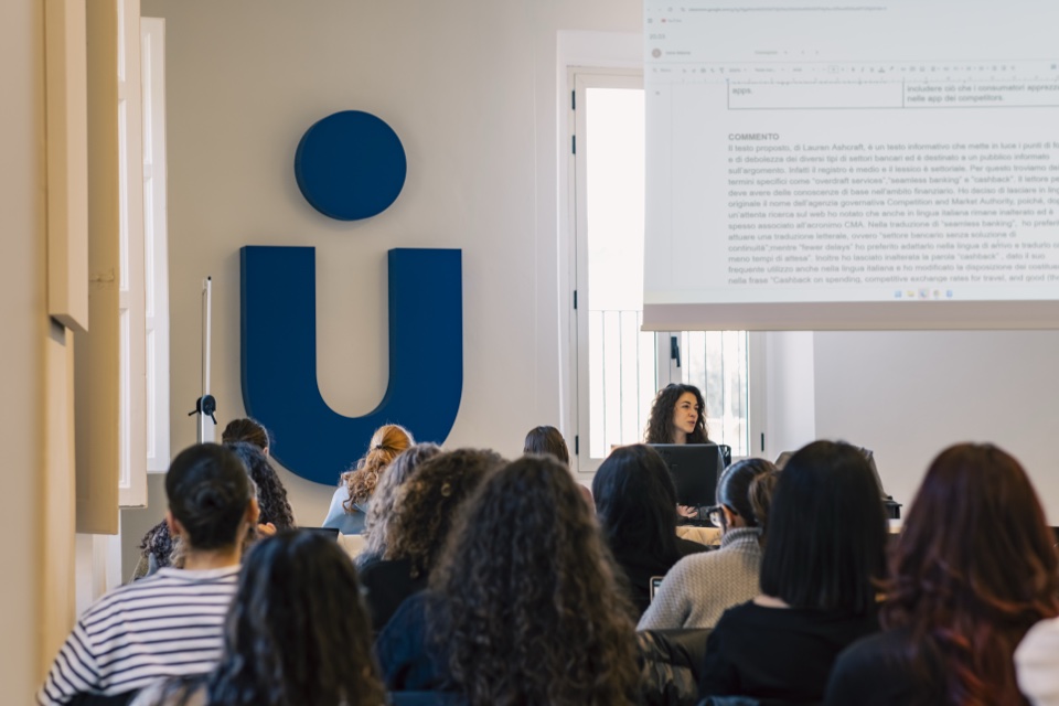 Students in a lecture hall with the Unicollege mark on the wall