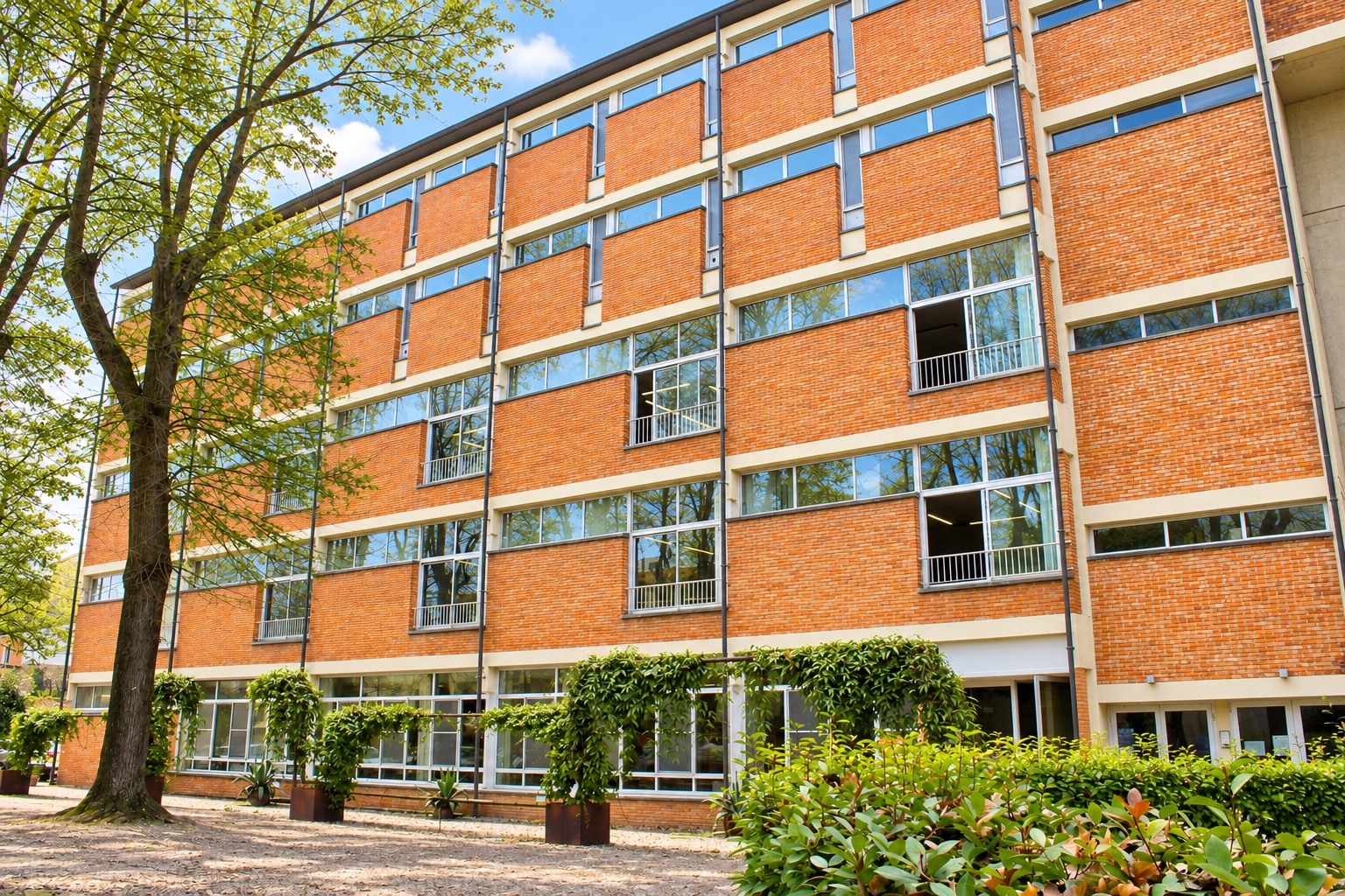 The brick facade of the Mantua campus seen from the garden