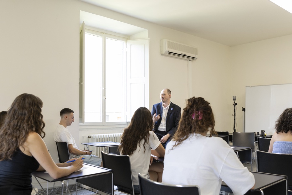 A professor leading a seminar, standing among the students