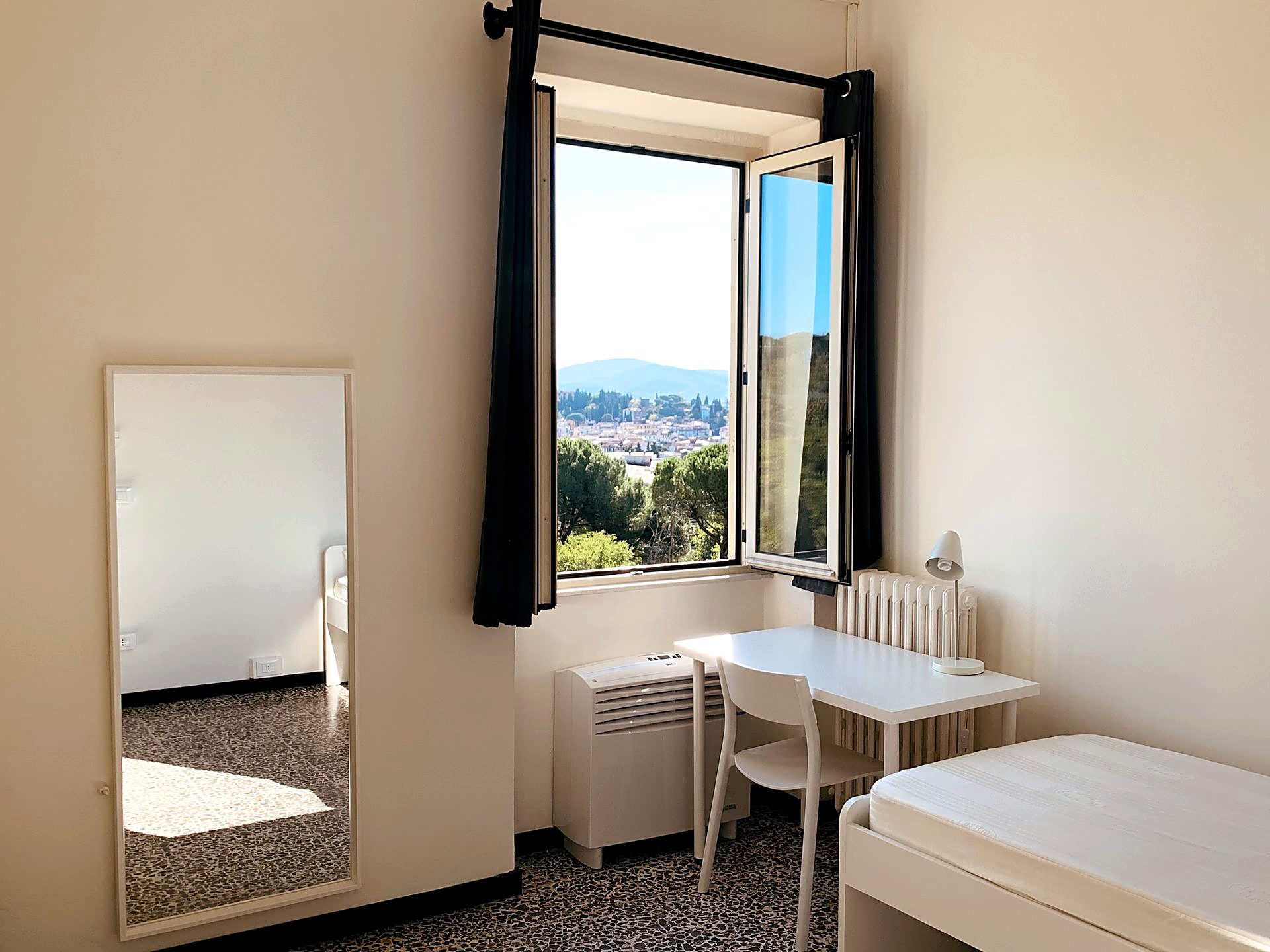 A student room in Florence, with a desk and a window onto the hills