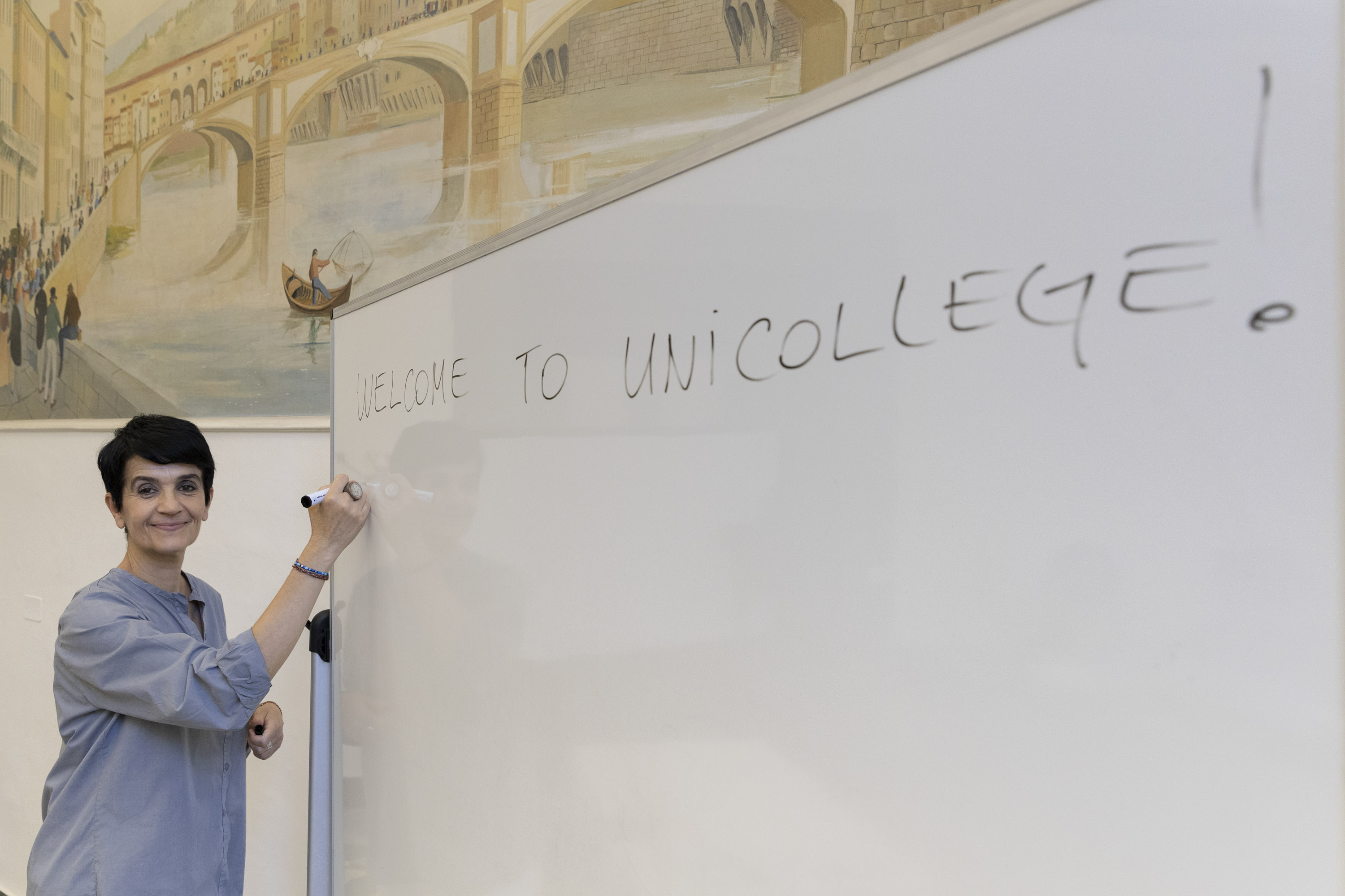 A member of the Unicollege team writing a welcome message on a classroom whiteboard