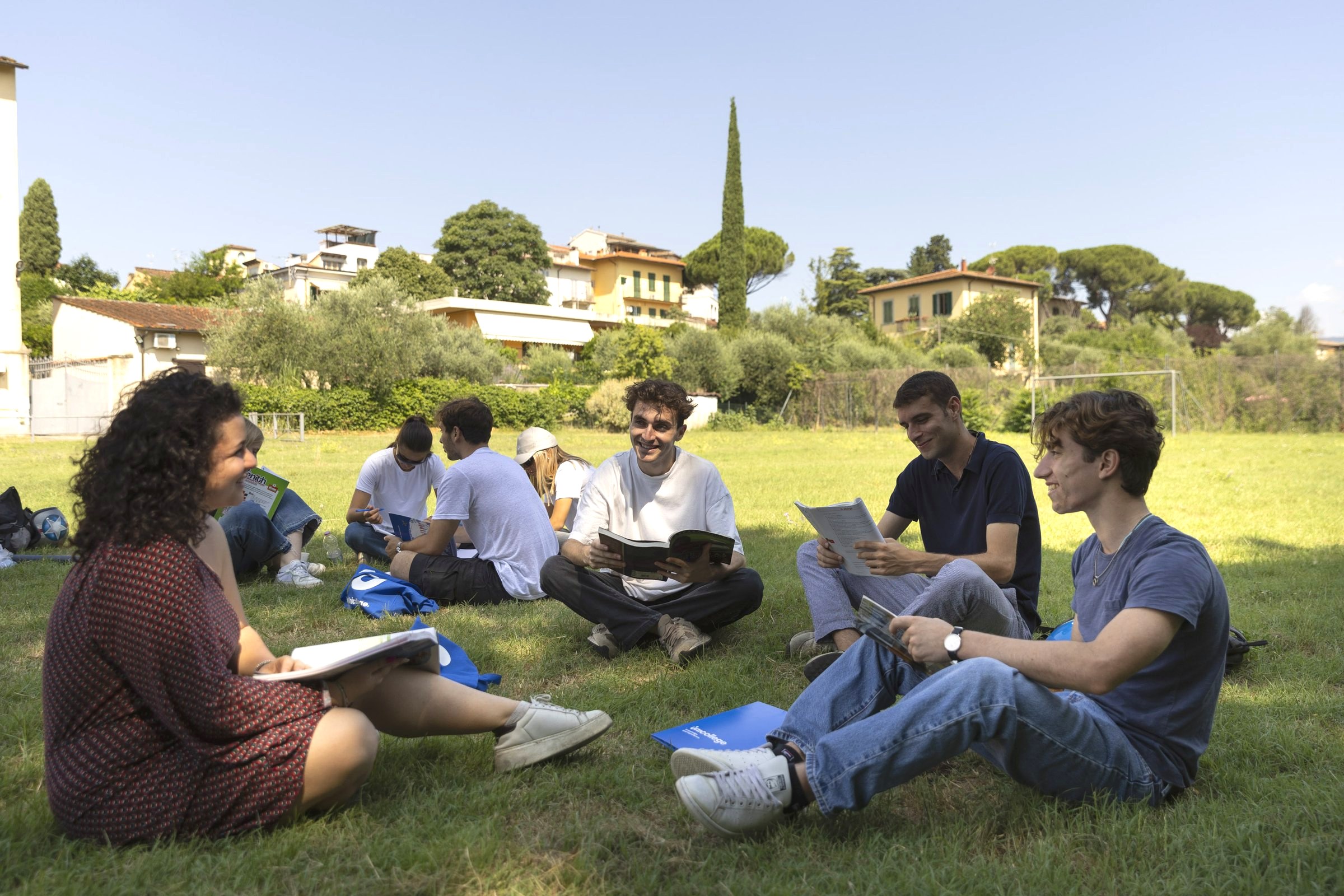 Students sitting together on the campus lawn with their course folders