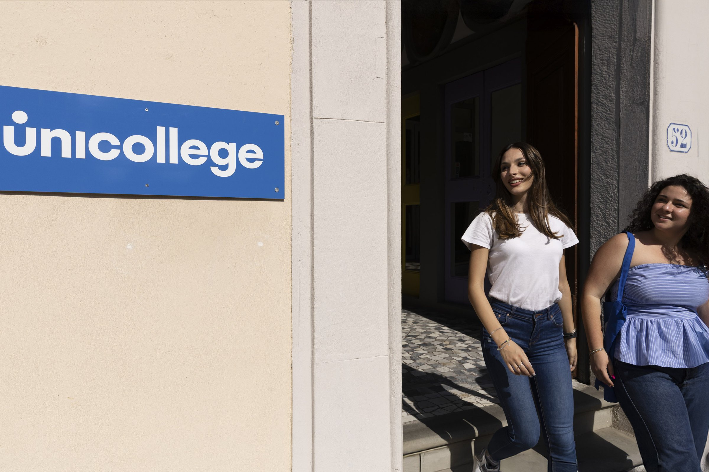 Two students walking out past the Unicollege entrance sign