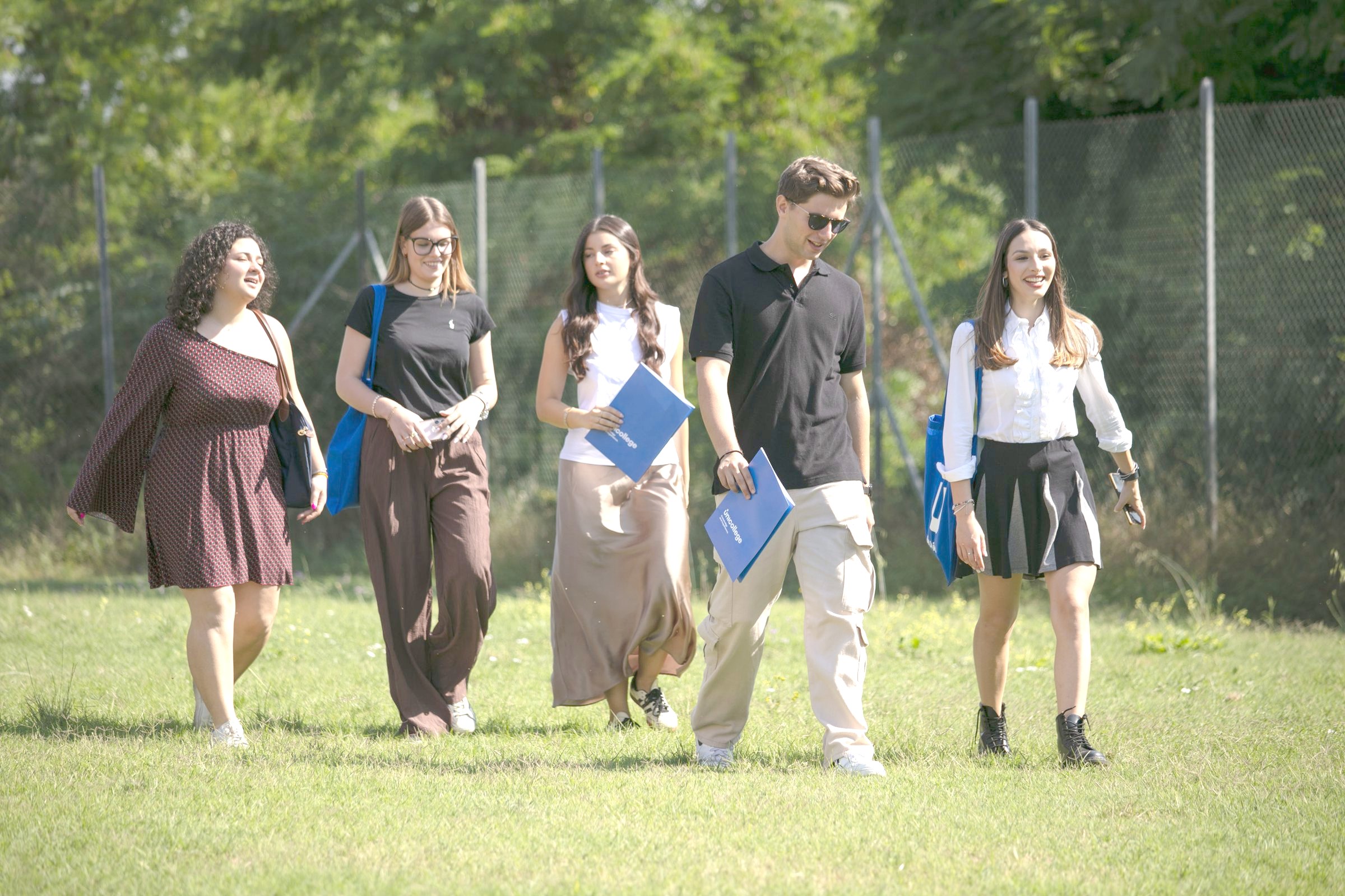 Students walking across the campus grounds with their course folders