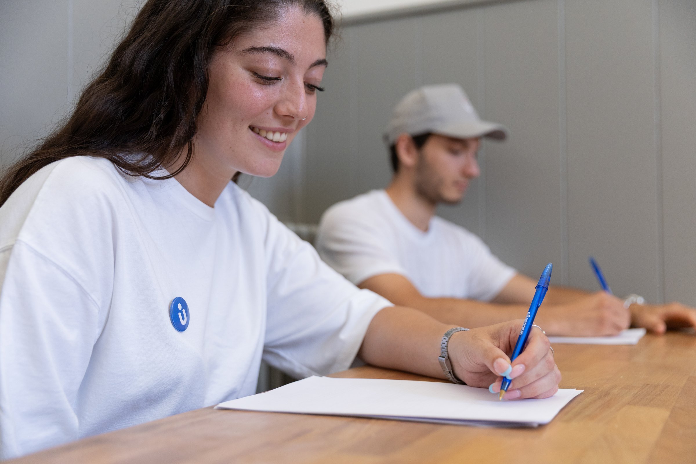 Two students taking notes side by side at a Unicollege desk