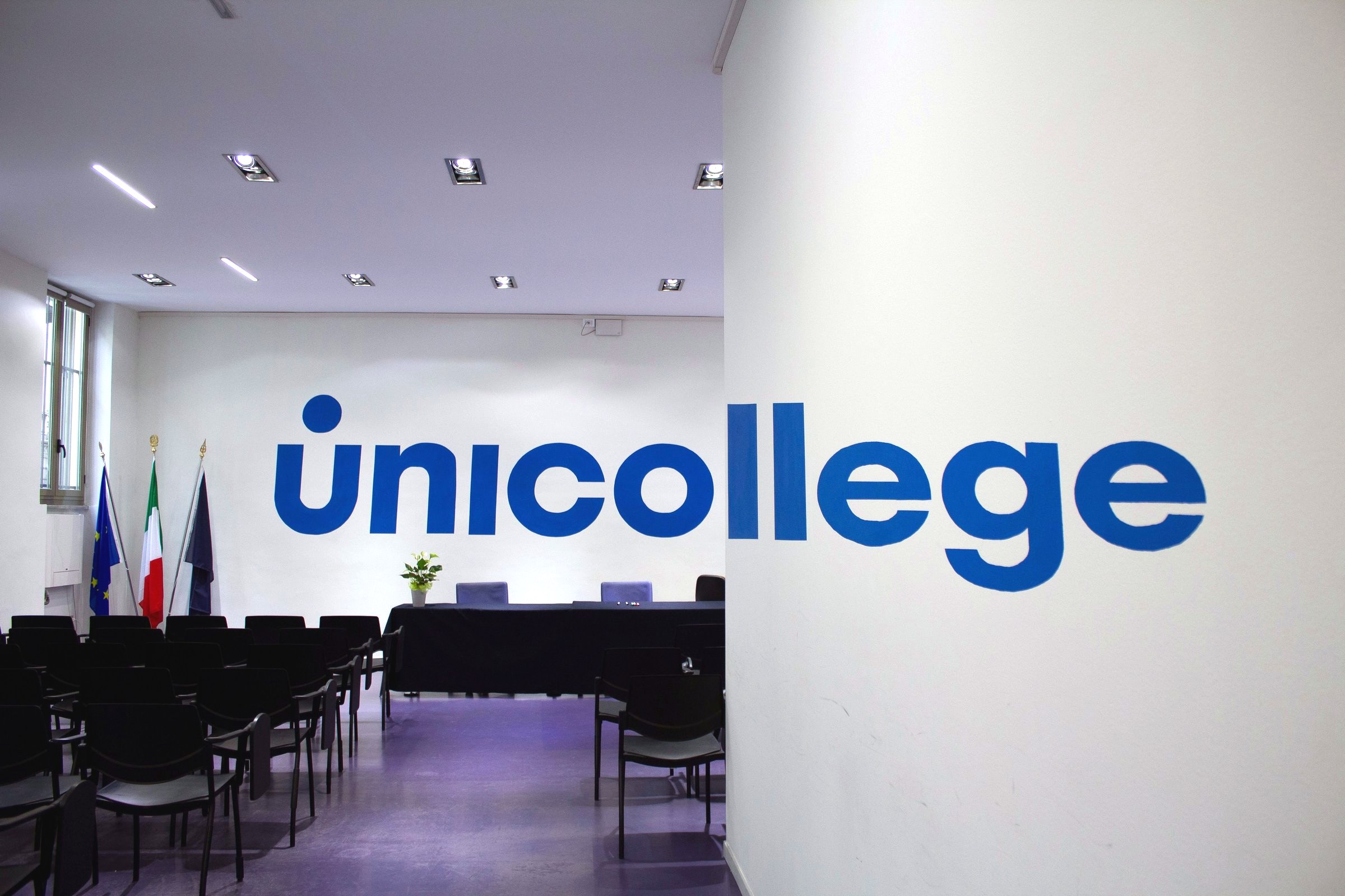 The Aula Magna of the Turin City College with the Unicollege wall mark and the flags