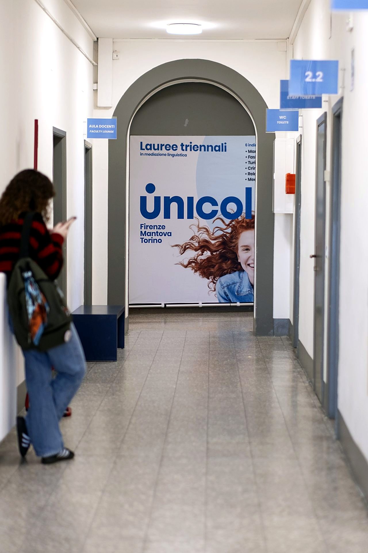 A student in the corridor of the Florence campus, next to the bachelor programs panel