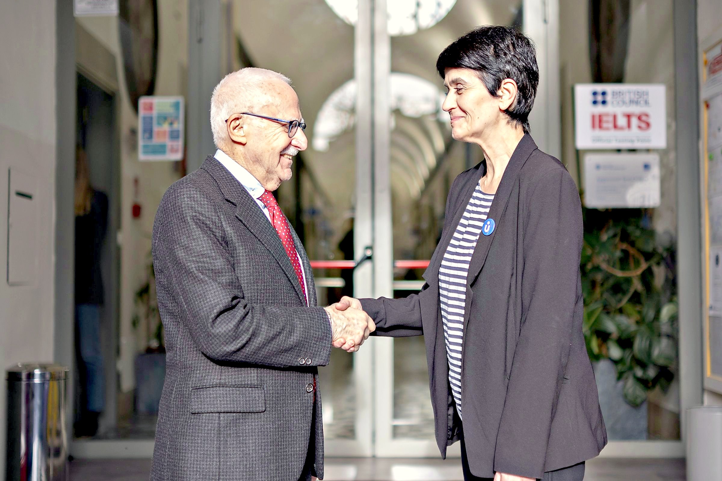 Two institutional representatives shaking hands at a Unicollege campus entrance
