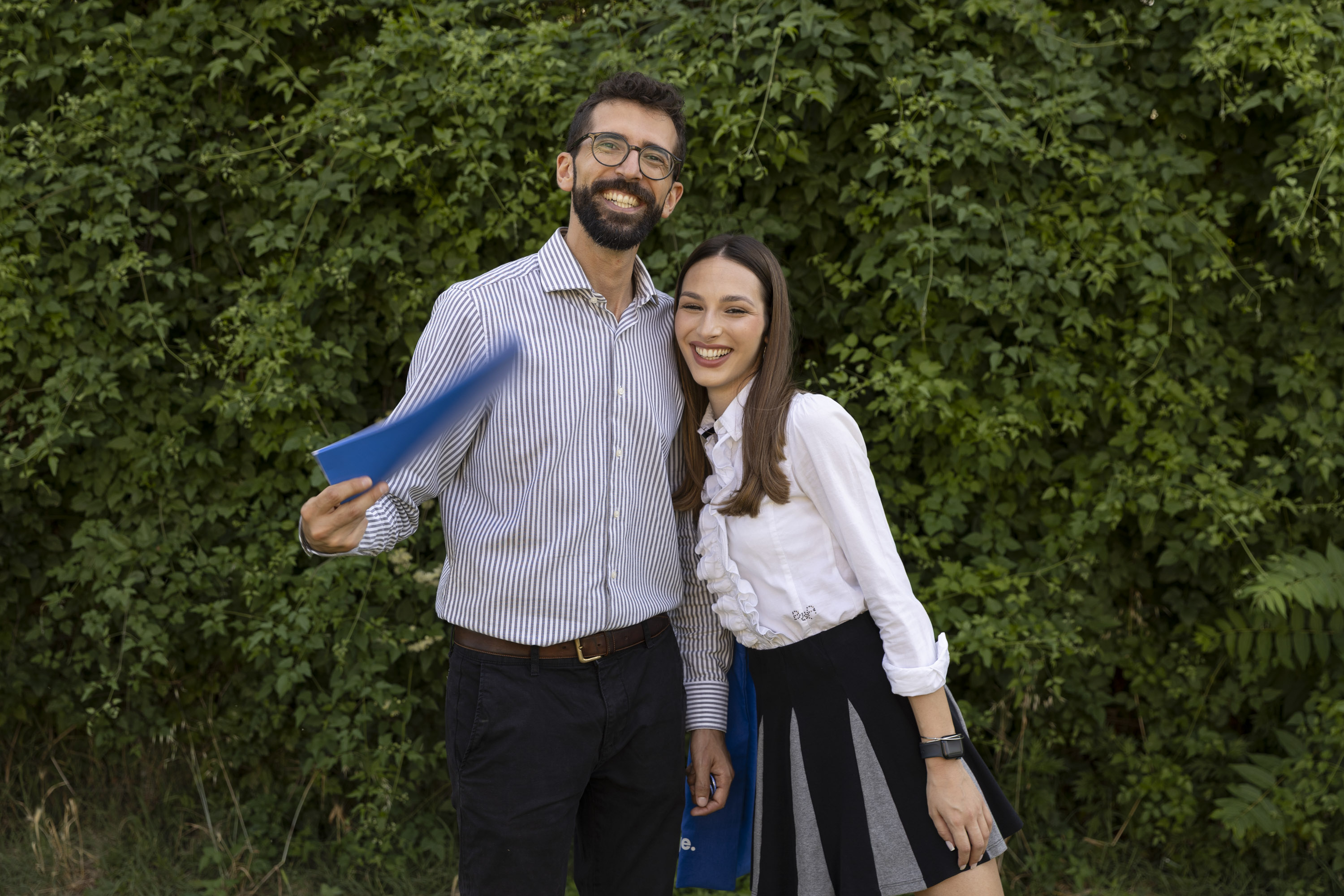 Students studying together on a sunny campus terrace surrounded by greenery